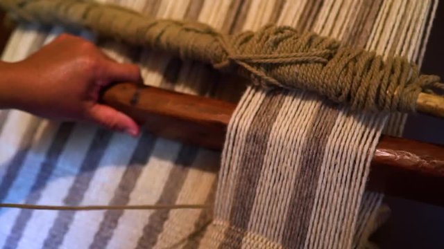 Close up in the hands of a woman weaving a beautiful natural woolen horse blanket. Trapa Trapa Alto Biobio. Chile. Flat plane