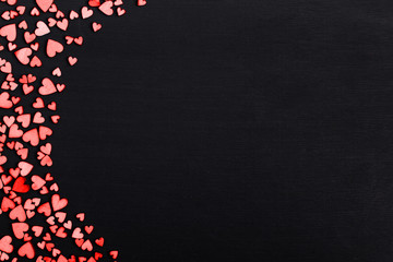 Wooden red hearts on a black table with place for text. Background for greeting card or congratulations on Valentine's Day. Copy space.