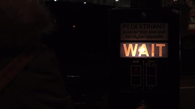 UK November 2018 - The word &sbquo;&Auml;&uacute;wait&sbquo;&Auml;&ugrave; lights up as a pedestrian pushes the crossing button and vehicles continue to pass by in the background.