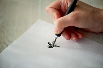 A woman's hand writes with ink, a fountain pen. Writing. The creative process of creating a work