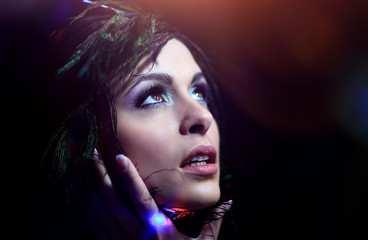 Beautiful black-haired woman with peacock feathers in studio sho