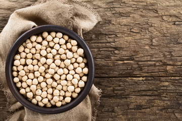Raw chickpeas or garbanzo beans (lat. Cicer arietinum) in rustic bowl, photographed overhead on...