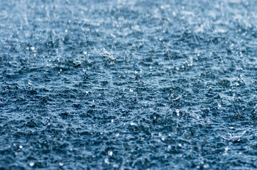 Fototapeta na wymiar Falling rain drops, splash on water surface
