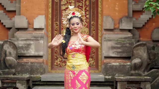 Slow motion of pretty balinese woman showing welcoming gesture while wearing traditional costume in a temple