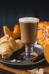 Pumpkin latte and croissant on the table with pumpkin slices