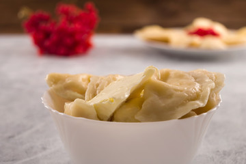 Cooked dumplings with a piece of butter in a white bowl.