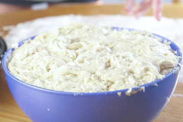 Preparation of yeast dough in a blue plastic bowl. Close-up view.