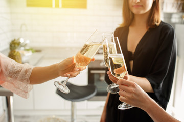 Merry christmas party. Close-up view of sexy, young girls clinking glasses of champagne on christmas night, at home