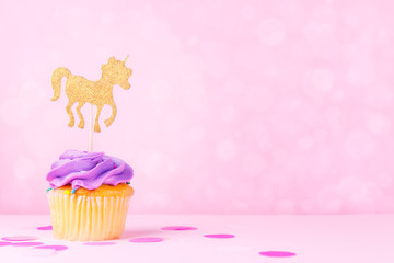 Creative pastel fantasy holiday card with cupcake, confetti and unicorn on bokeh backdrop. Baby shower, birthday, celebration concept.