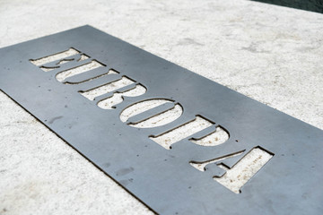 Fototapeta premium Metal label un marble with name of the continent Europe. Close up detail.