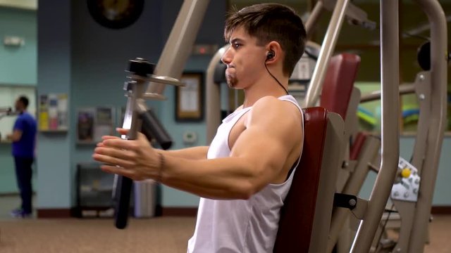 Closeup of young bodybuilder working the pec dec in a fitness club.