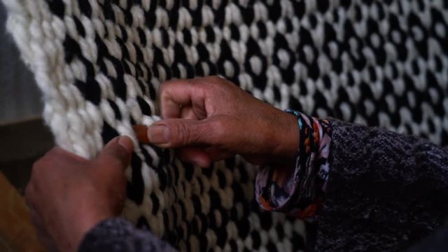 Hands of a lady weaving a natural wool horse riding blanket. Trapa Trapa Alto Biobio. Chile. Flat plane