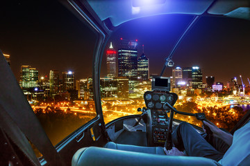 Helicopter cockpit interior flying on Central business district reflecting on Swan River. Scenic flight above Perth, Western Australia skyline. Night urban aerial scene.