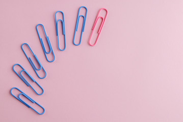 Colored paper clips on a pink background.