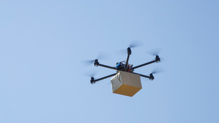CLOSE UP: Drone delivery, multirotor helicopter flying big brown post package