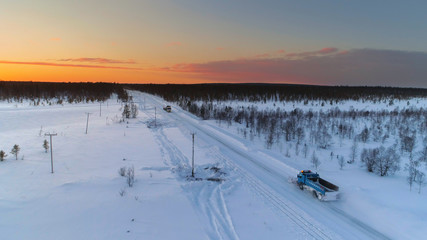 AERIAL: Snowplow driving and plowing through snow covered highway amidst forest