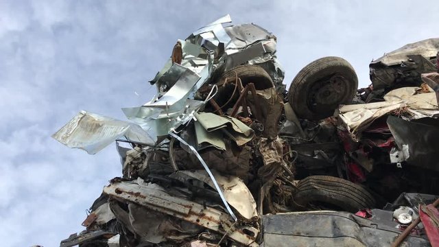 Junk yard art metal dangling from cars in sunlight with camera shooting skywards.