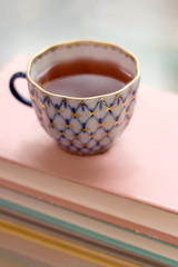 Tea in a vintage cup on stack of books. Selective focus.