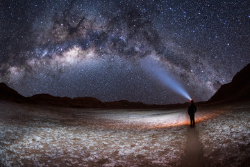 A person at night,  shining a light on the Milky Way Galaxy in the Valley of the Moon or Valle de...