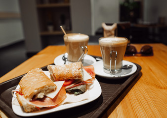 Typical Spanish breakfest snack - coffee latte and bocadillo sandwich on table in one cafe in Barcelona Spain