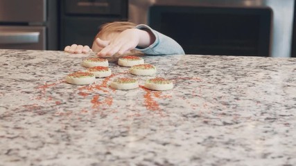 Slow motion video of a toddler stealing a fresh baked cookie off of the kitchen counter top - Powered by Adobe