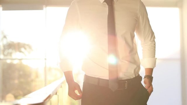 Young businessman checking time in sunlit office