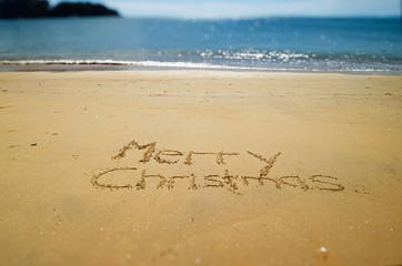 Merry Christmas hand written in the golden sands of Kaiteriteri Beach, New Zealand