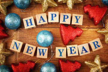 New Year festive image with a text on wooden cubes and bright colorful toys on wooden background