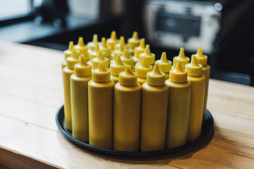 Bottles with mustard on tray in restaraunt interior