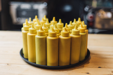 Bottles with mustard on tray in restaraunt interior