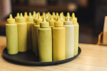 Bottles with mustard on tray in restaraunt interior