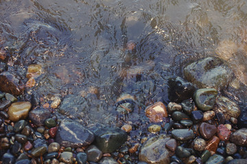 Background of wet stones and water on the river bank.