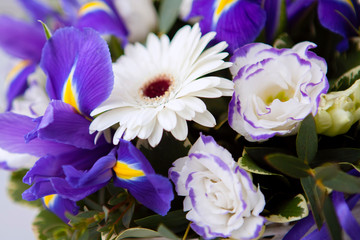 Flower arrangement bouquet of rose, iris in a wicker basket on a gray wooden background.