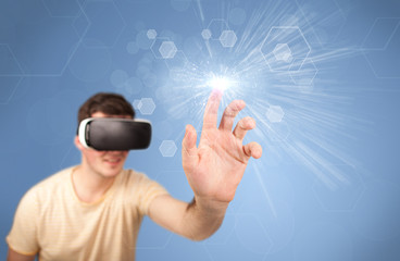 Young impressed man wearing virtual reality goggles with blue hexagons around him 