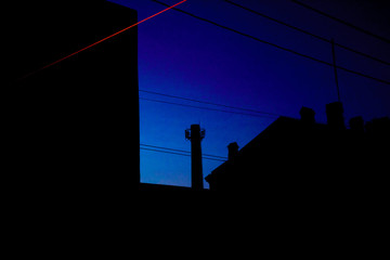 Night silhouette of roofs with pipes and electrical wire