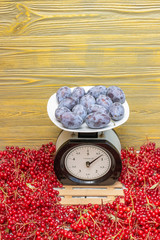 Сливы лежат на механических весах.