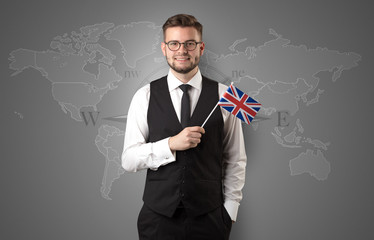 Cheerful businessman standing in front of a map with flag on his hand
