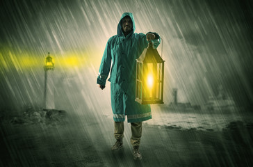 Man at the coast coming in raincoat with glowing lantern concept

