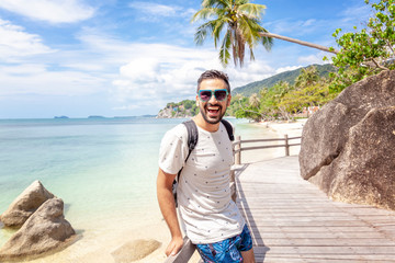 Handsome happy man wearing white T-shirt at the sea or the ocean background. Travel vacation...