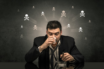 Loser drunk man sitting at table with skulls concept around
