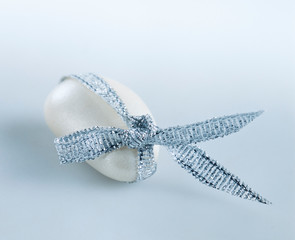 White candy-coated almond tied with a silver ribbon
