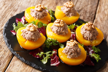 Festive appetizer of peaches stuffed with canned tuna mousse and walnuts, served with leaf salad close-up. horizontal