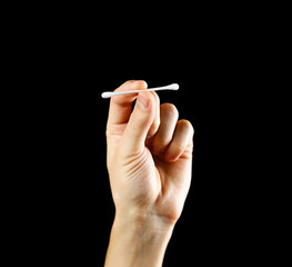 Hand holding a white cotton swab. Close up. Isolated on black background