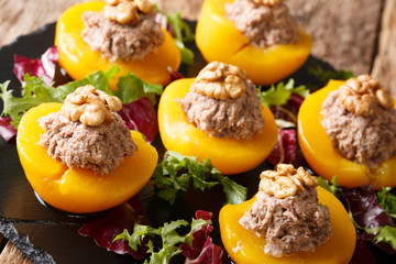 beautiful starter of peaches stuffed with tuna mousse and decorated with walnuts close-up. horizontal