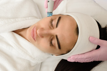 Obraz na płótnie Canvas Young woman having ultrasound face peeling in spa salon