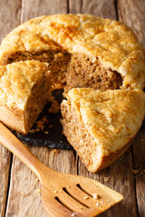 Delicious hearty pie with pork, mashed potatoes and spices close-up. vertical