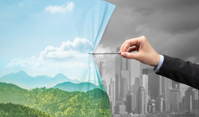 hand pulling green cityscape curtain to gray cityscape, environmental protection concept