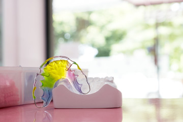 Dental retainer orthodontic appliance on the colour background.