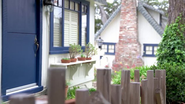 young girl photographer walking out from the traditional american old building. asian traveler with camera through the green garden. white house with chimney in sunny day.