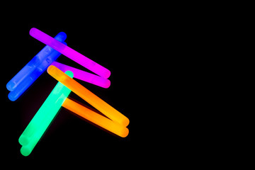 Colorful fluorescent light neon big glow stick on mirror reflection black background